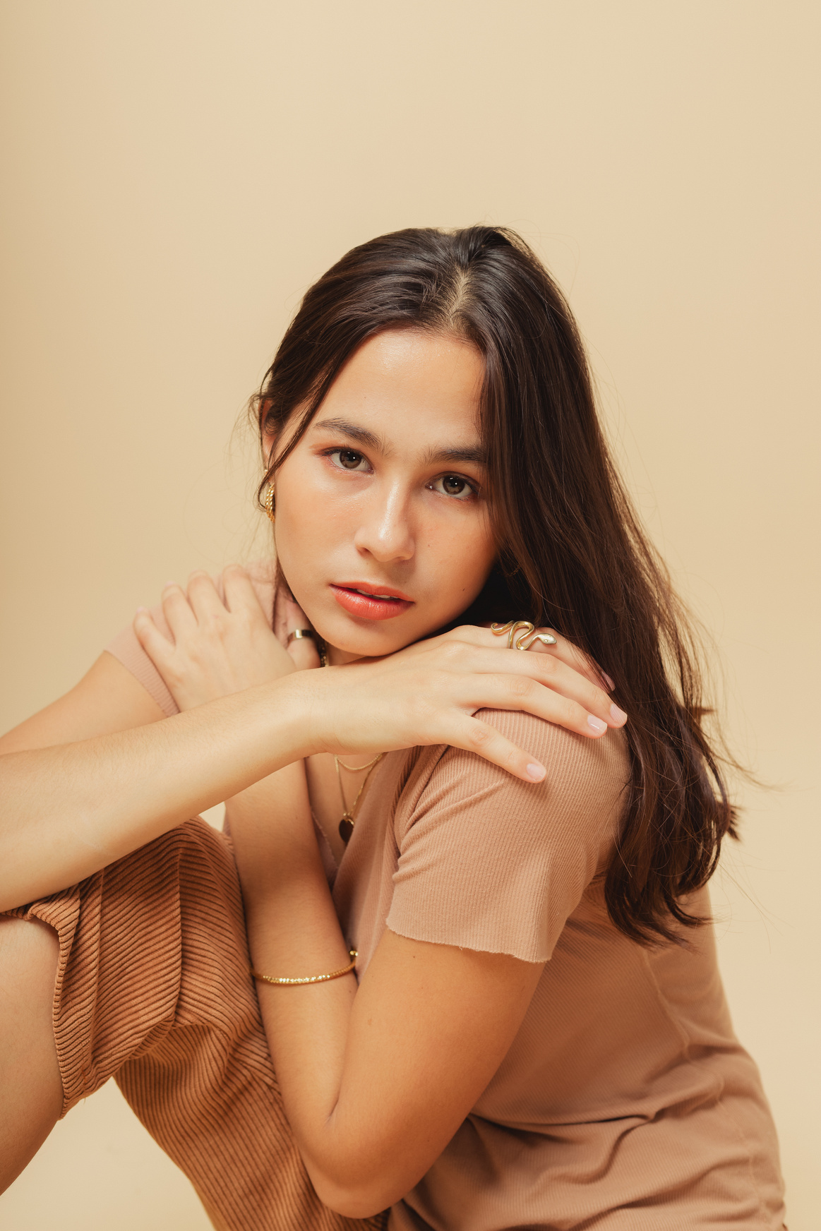 Woman in Brown Shirt with Jewelry on Beige Background